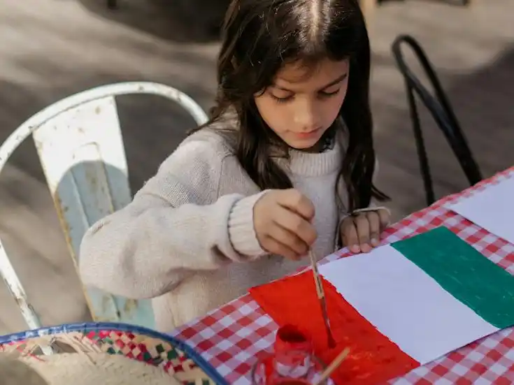 Coloreando su futuro con esperanza, una niña dibuja la bandera
